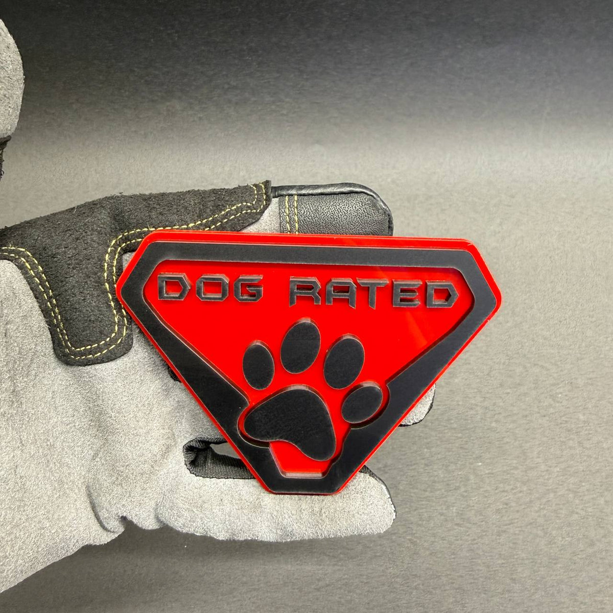 Custom Dog Rated car badge featuring a bold black paw print, raised lettering and bright red background with a black shield outline.