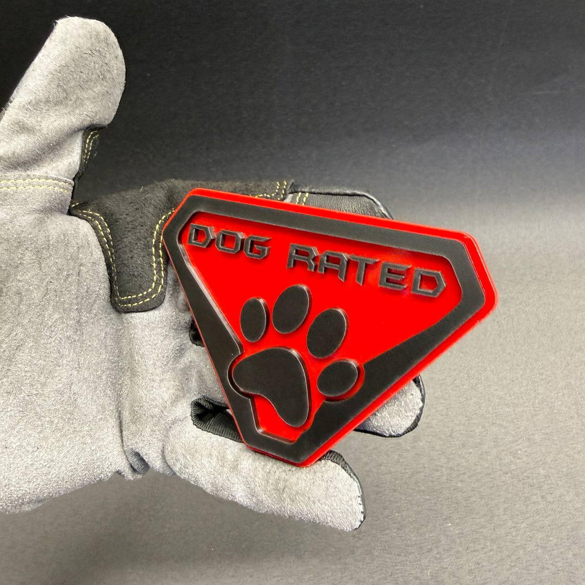 Decorative Dog Rated car emblem with raised black paw print and lettering, ideal for pet owners, dog lovers and personalized automotive accessories.