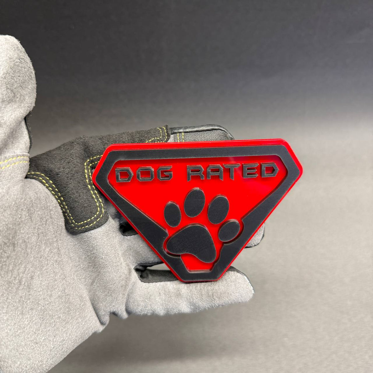 Dog Rated automotive badge with black raised lettering and large paw print, suitable for decorative styling on Chevrolet Silverado and GMC Sierra trucks.