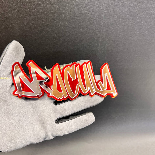 Red and mirror silver DRACULA automotive fender badge held in hand