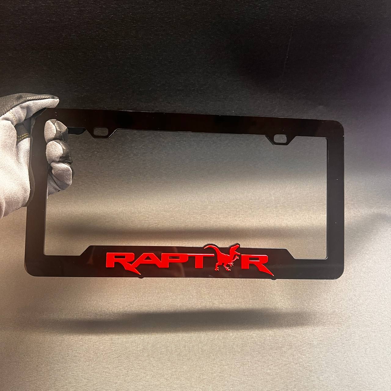 Raptor car license plate frame in glossy black with red logo design