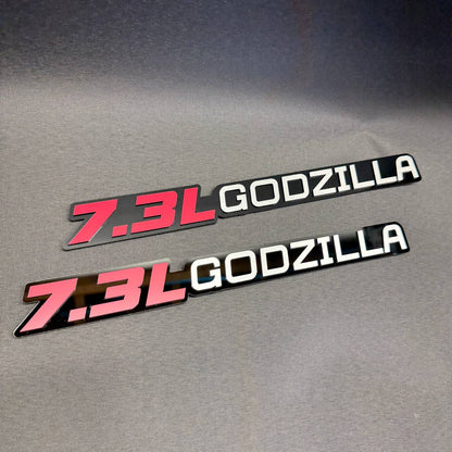 Ford 7.3L Godzilla V8 engine car badge with red lettering, white Godzilla text and glossy black background.
