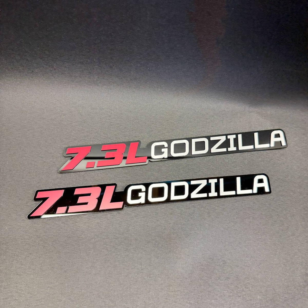 Ford F350 7.3 liter Godzilla V8 aftermarket engine badge featuring red 7.3L lettering and white Godzilla design.