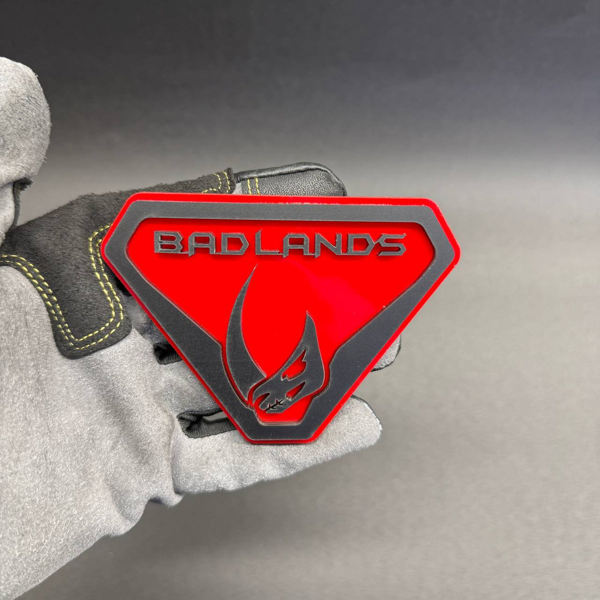 Custom Bronco Mudhorn Badlands car badge featuring a red background, black raised lettering and Mudhorn skull design for off-road vehicle styling.