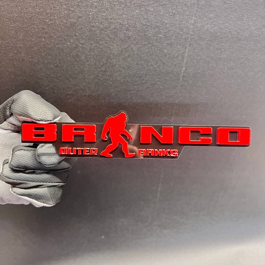 Red and black Bronco Sasquatch Outer Banks car badge with Bigfoot silhouette