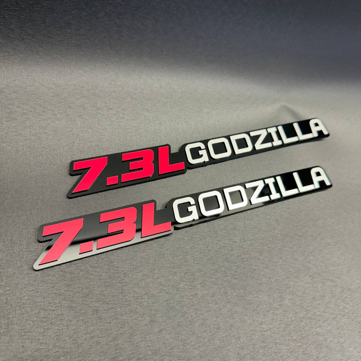 Ford 7.3L Godzilla V8 performance engine emblem with contrasting red lettering and black acrylic backing.
