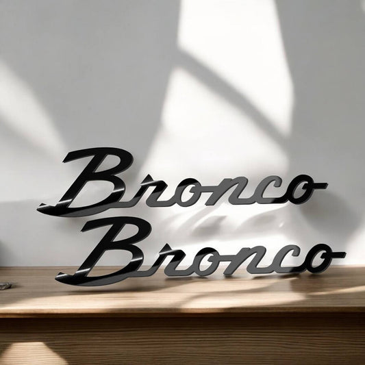 Gloss black script-style badges on tabletop with light reflections