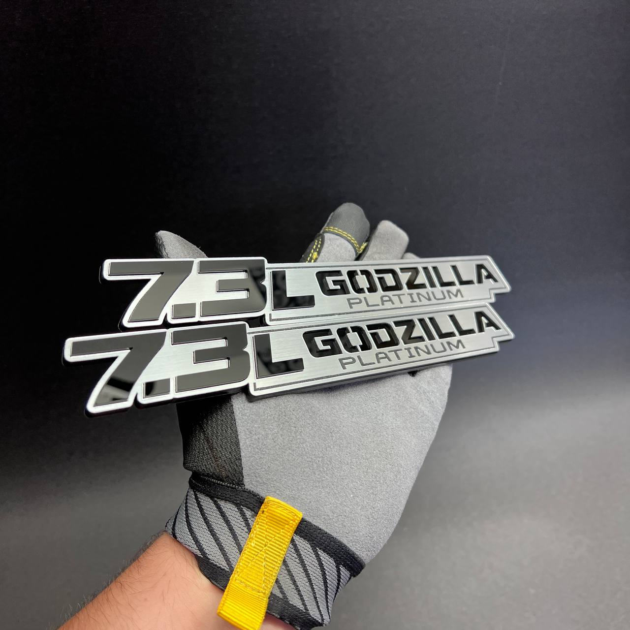7.3L Godzilla Platinum emblem set shown on glove with brushed silver finish