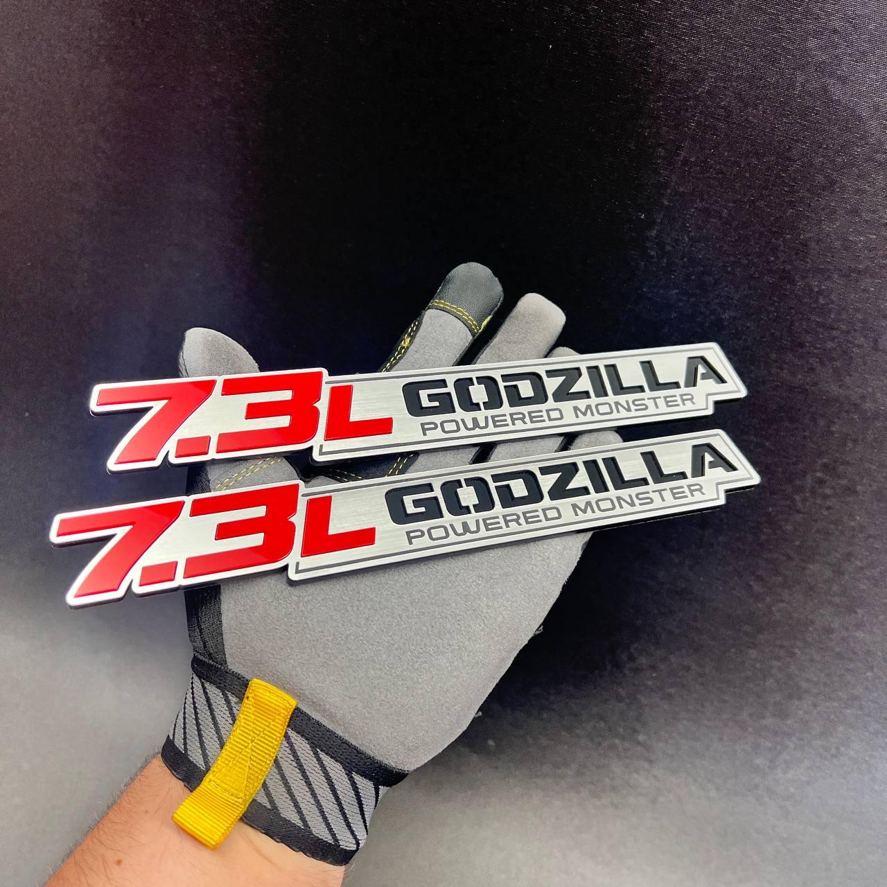 Custom 7.3L Godzilla performance car emblems displayed on a work glove