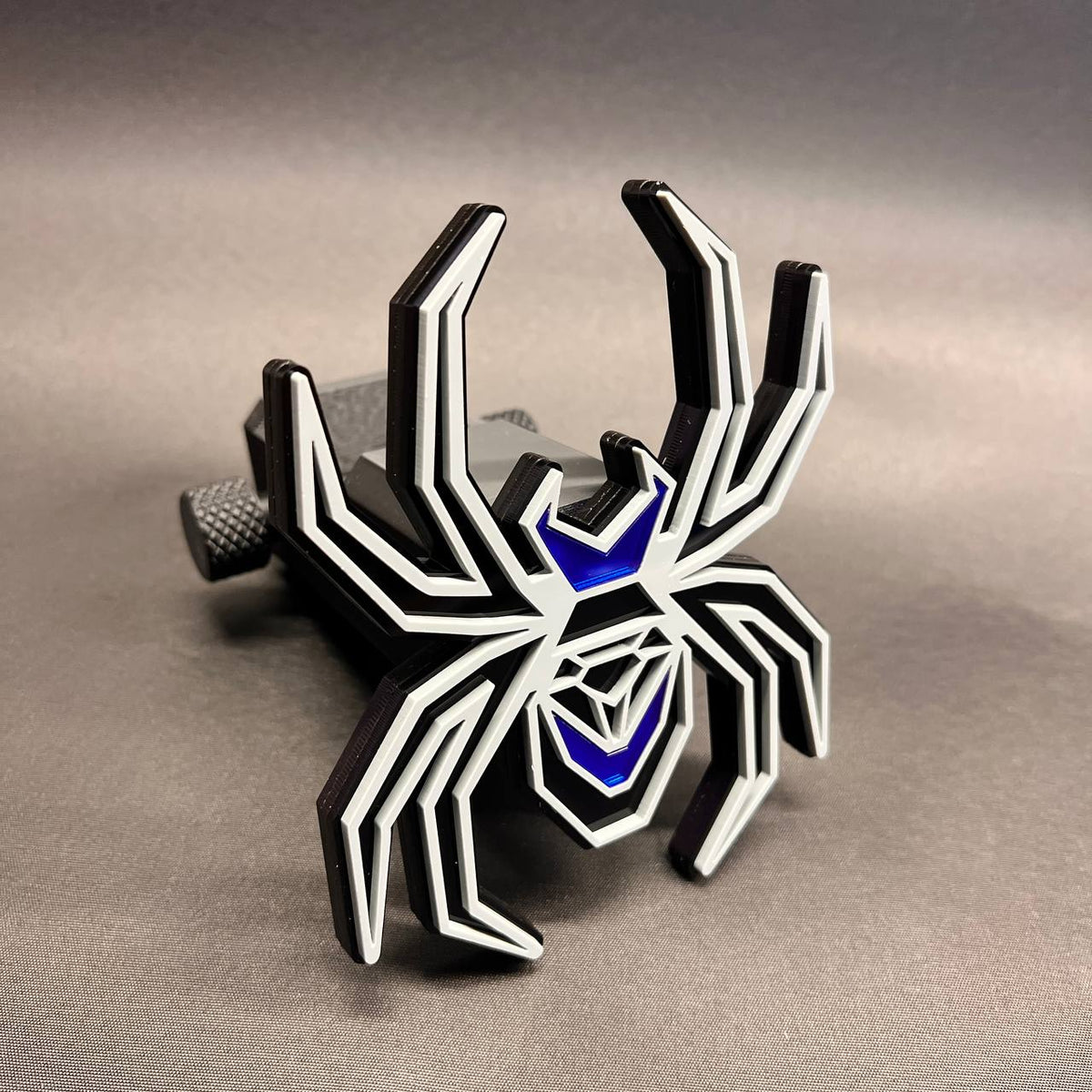 Black and gray spider truck hitch cover featuring bright mirror blue accent panels.