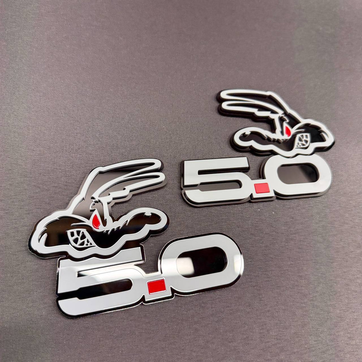 Coyote 5.0 V8 custom car badge with cartoon coyote head, gray accents, black backing and contrasting red eye design.