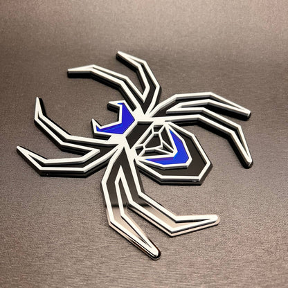 Custom spider car badge in gray on black with reflective blue details for fender installation.