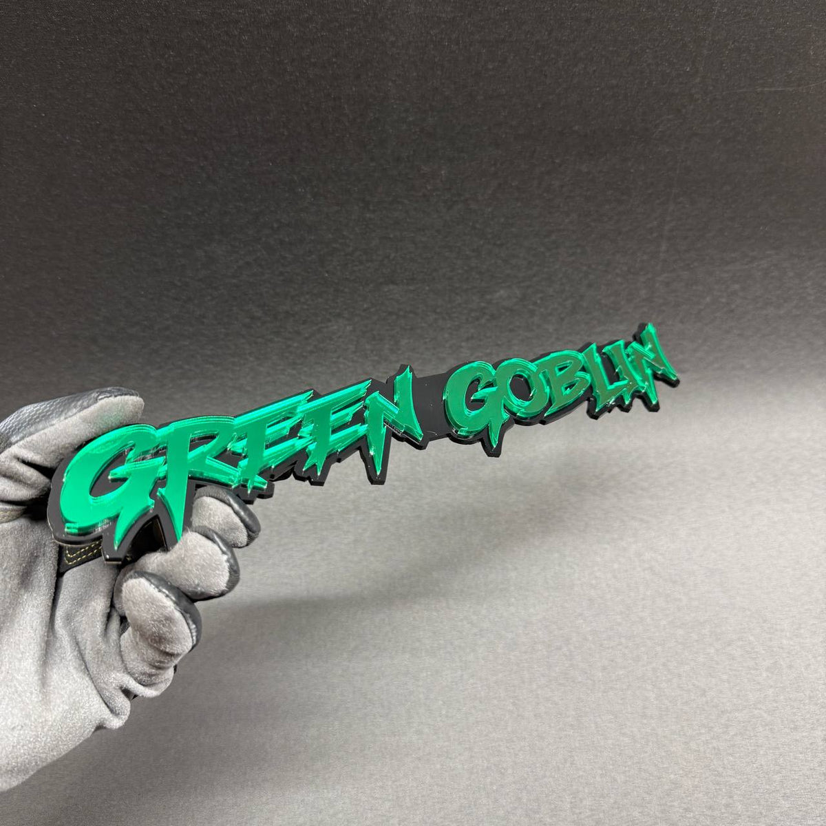 Green Goblin automotive emblem with aggressive comic style typography, green reflective letters and black background, custom exterior badge for Dodge Challenger and Charger.