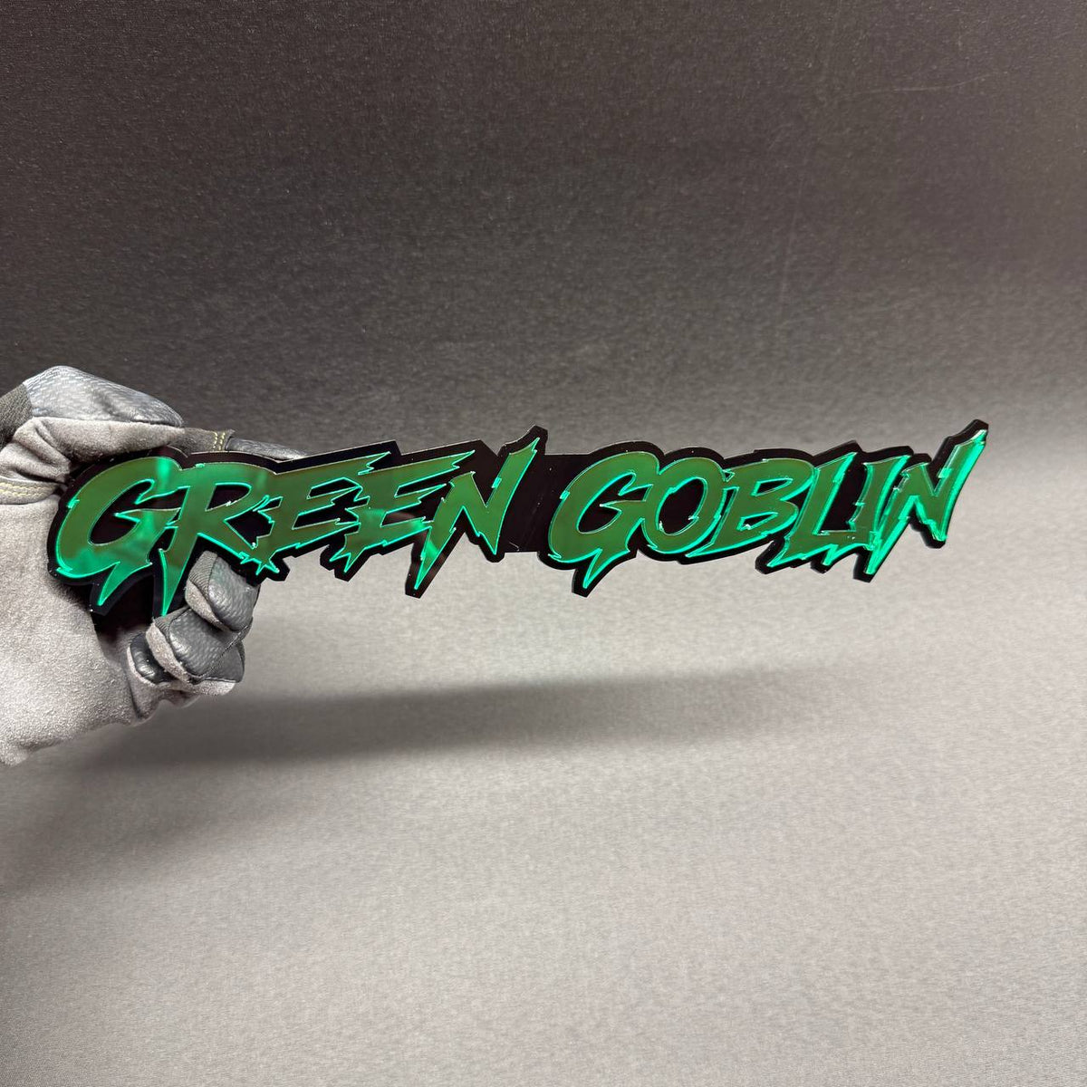 Green Goblin custom car badge featuring metallic green lettering with glossy black backing, Marvel villain themed fender emblem for Ford Mustang and Shelby builds.
