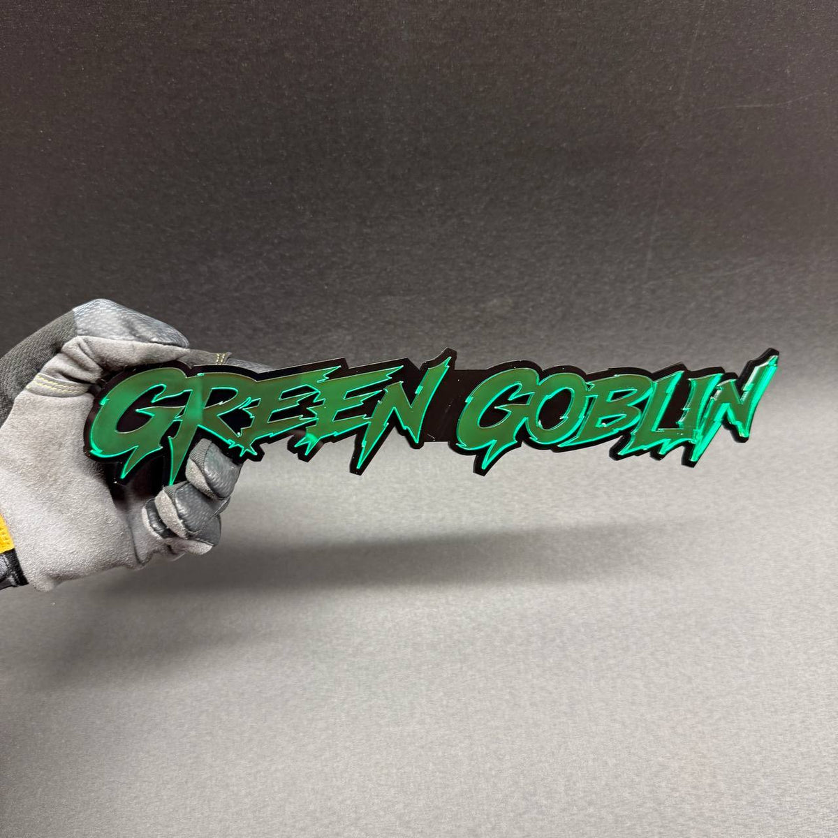 Green Goblin custom grille badge with sharp graffiti inspired lettering, superhero themed exterior accessory for Jeep Wrangler, Gladiator and custom off-road vehicles.