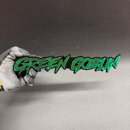 Green Goblin custom grille badge with sharp graffiti inspired lettering, superhero themed exterior accessory for Jeep Wrangler, Gladiator and custom off-road vehicles.