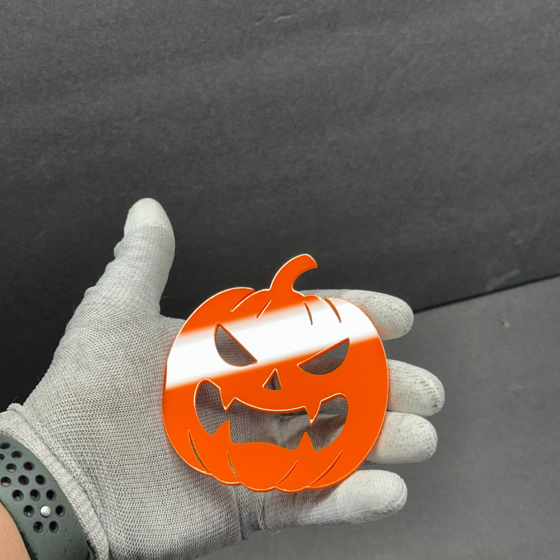 Halloween pumpkin tailgate emblem shown on gloved hand