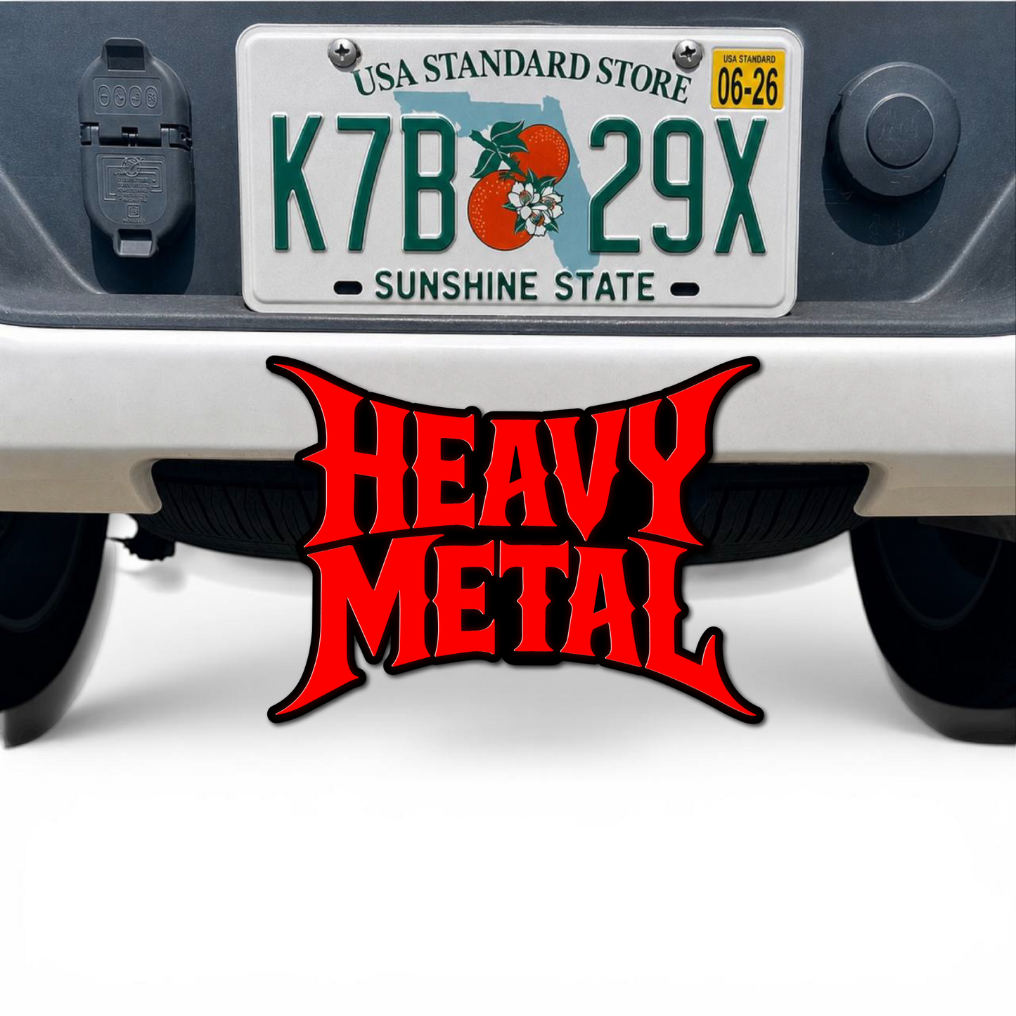 Heavy Metal 3D hitch cover car badge in red and black mounted below a truck license plate