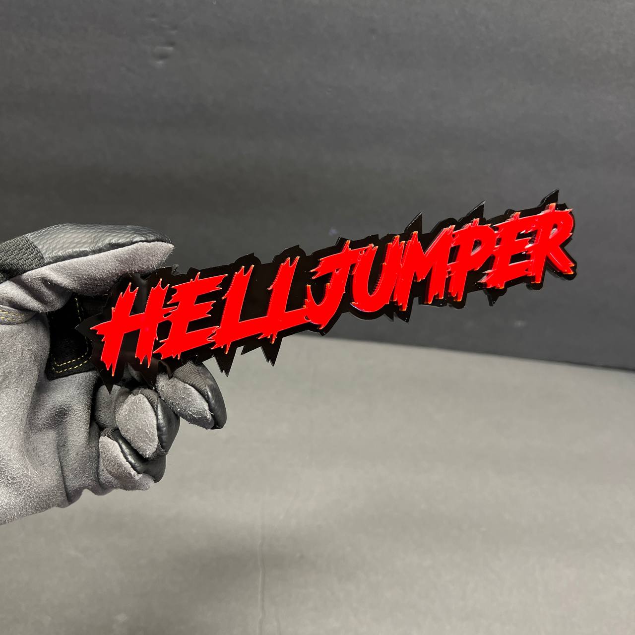 Red and black Hell Jumper acrylic car badge fender emblem with aggressive graffiti style lettering.