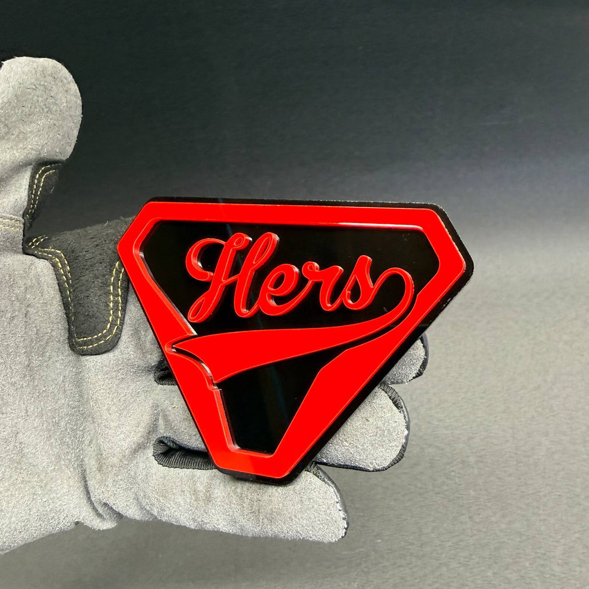 Red and black Hers car emblem with superhero-style shield design, decorative aftermarket badge for female drivers and car enthusiasts.