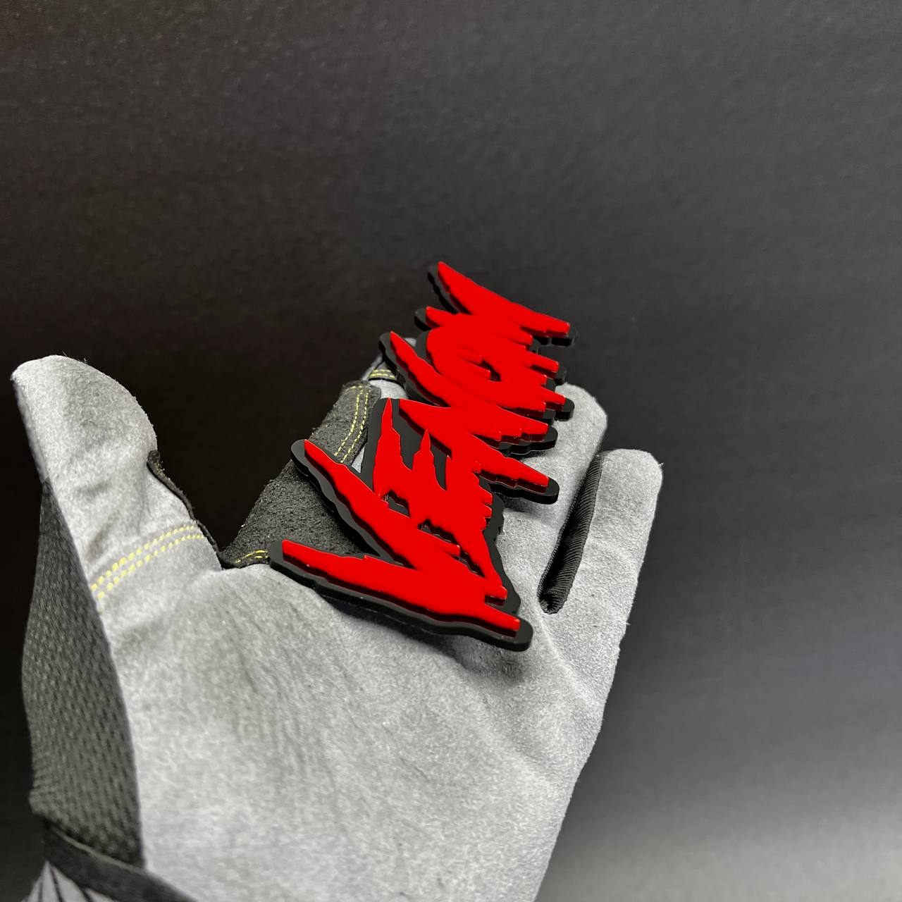 Custom laser cut acrylic text badge with sharp venom style lettering design