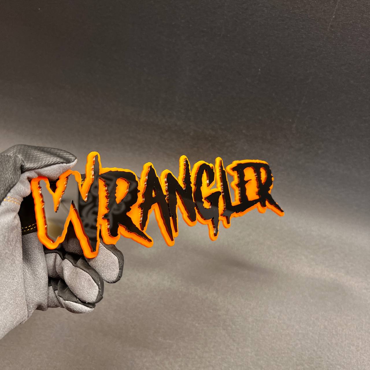 Custom Wrangler text badge with automotive-grade 3M adhesive backing.
