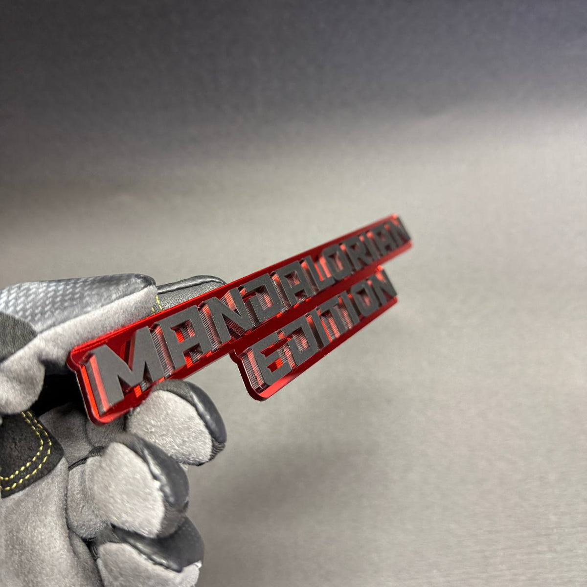 Star Wars Mandalorian Edition aftermarket tailgate badge with silver lettering and red acrylic backing, themed vehicle accessory for Jeep Wrangler and Gladiator.