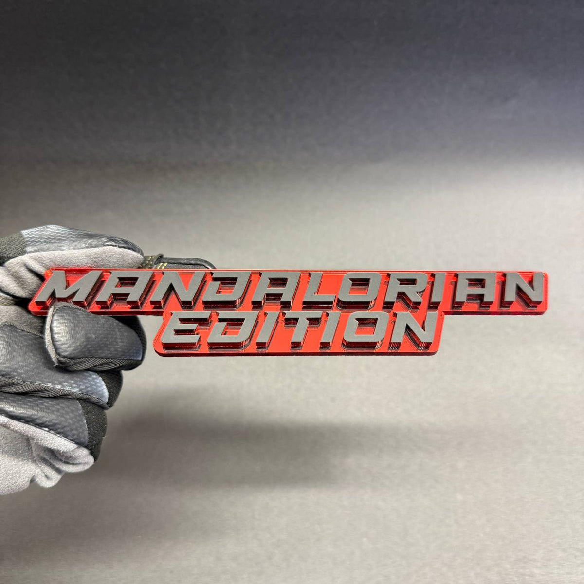 Star Wars inspired Mandalorian Edition grille emblem with bold silver lettering and glossy red backing, decorative badge for Toyota Tacoma and Tundra.