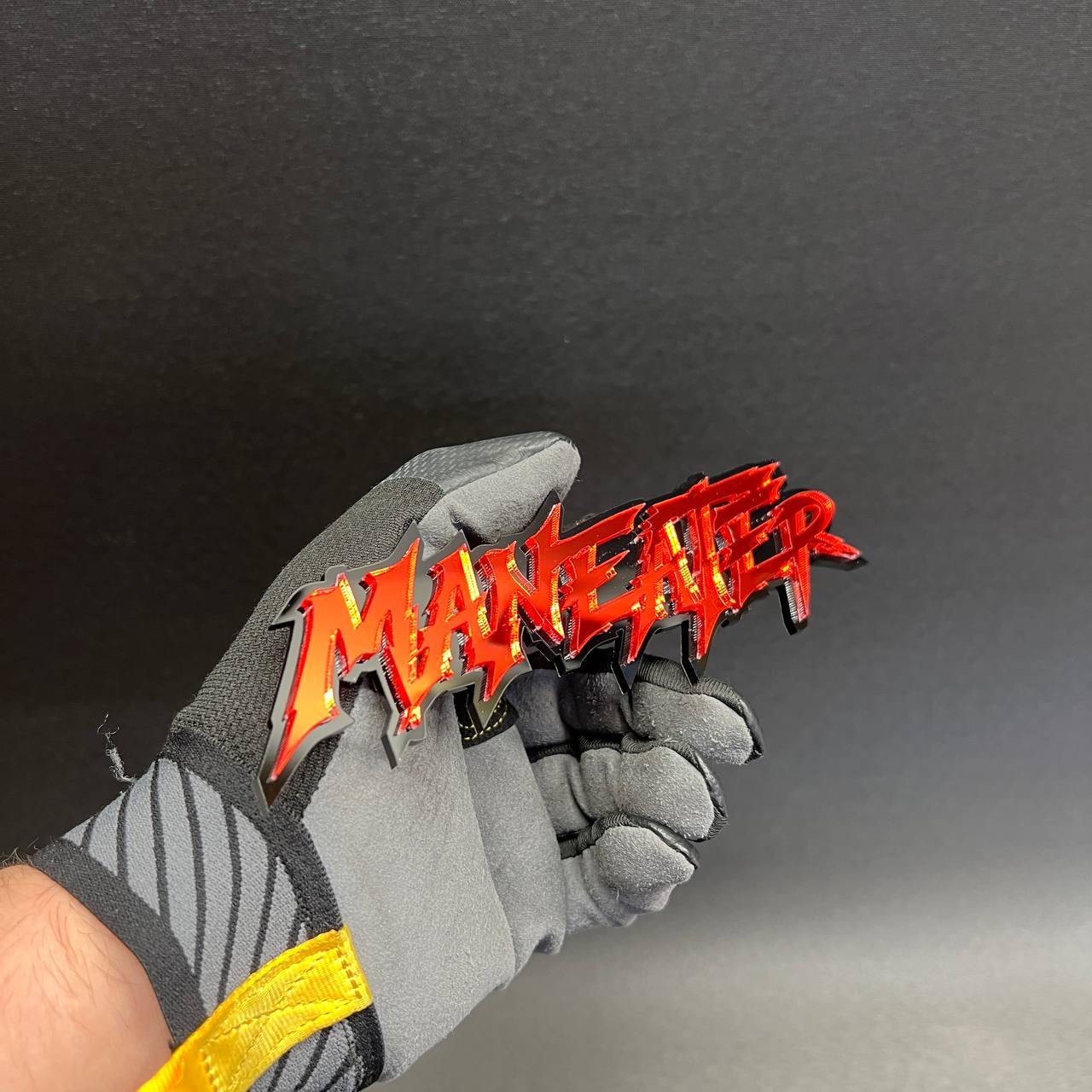 Glossy red MANEATER automotive emblem mounted with black acrylic outline