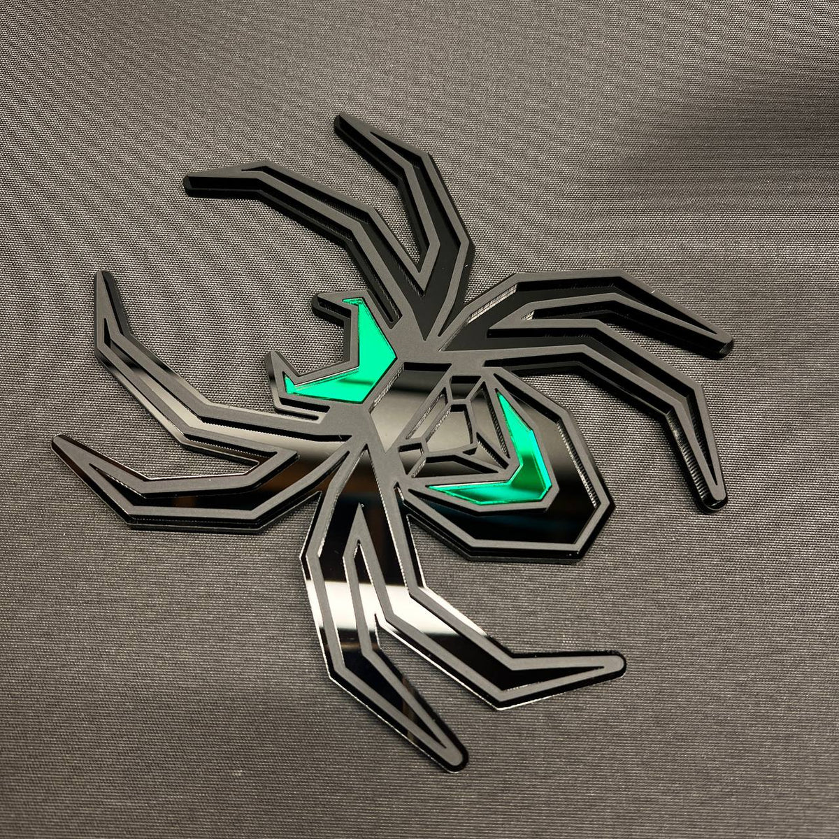 Matte black spider car badge with green details designed as a custom trailer hitch cover.