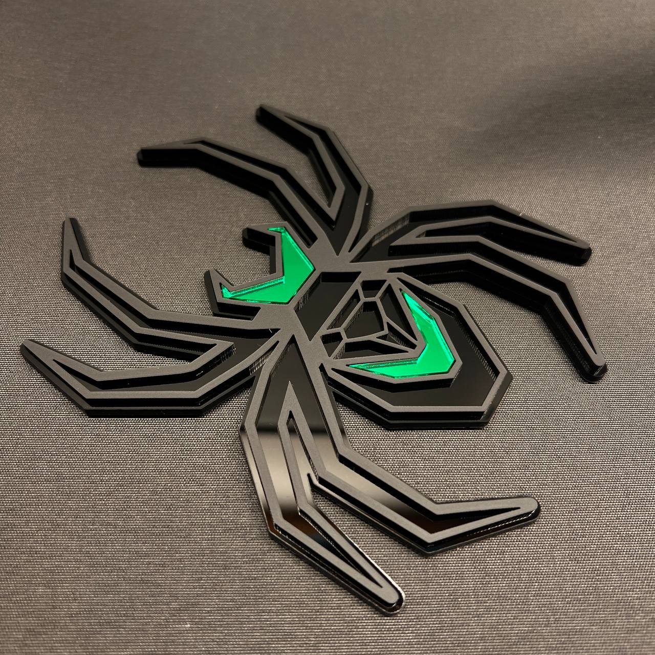 Matte black Black Widow spider hitch accessory with bright green accent panels.