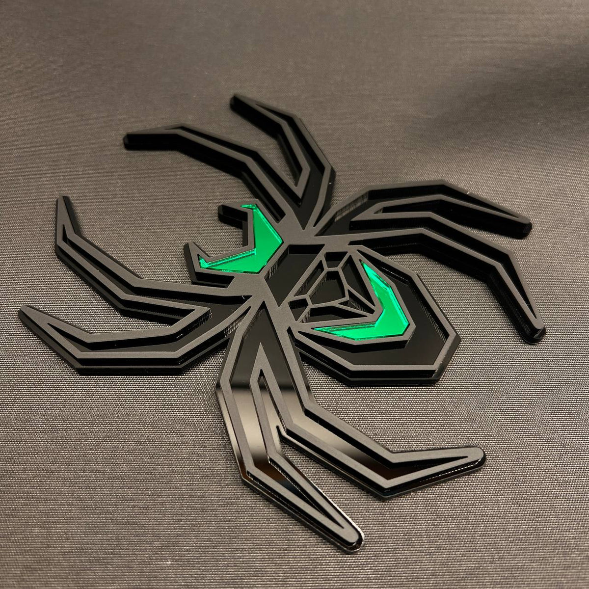 Matte black Black Widow spider hitch accessory with bright green accent panels.