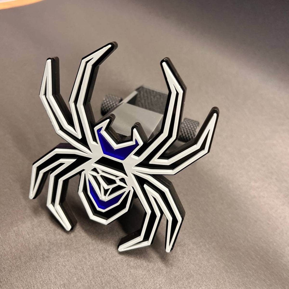 Custom spider trailer hitch receiver cover in gray, black, and mirror blue finish.