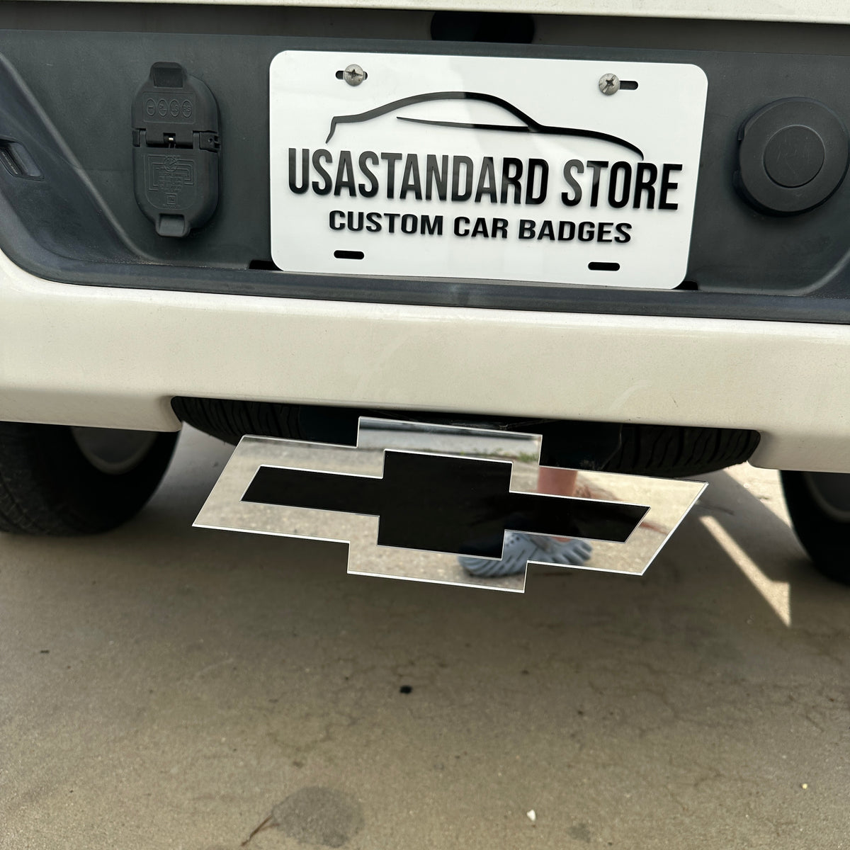 Silver and black Chevy Bowtie hitch cover installed on rear truck hitch