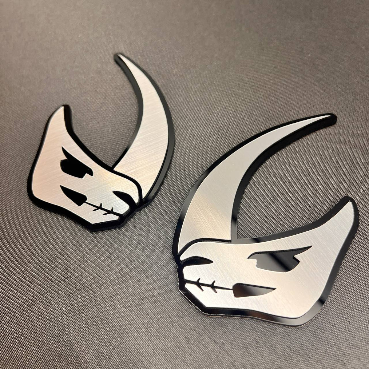 Brushed metal Mudhorn vehicle badge with black layered outline