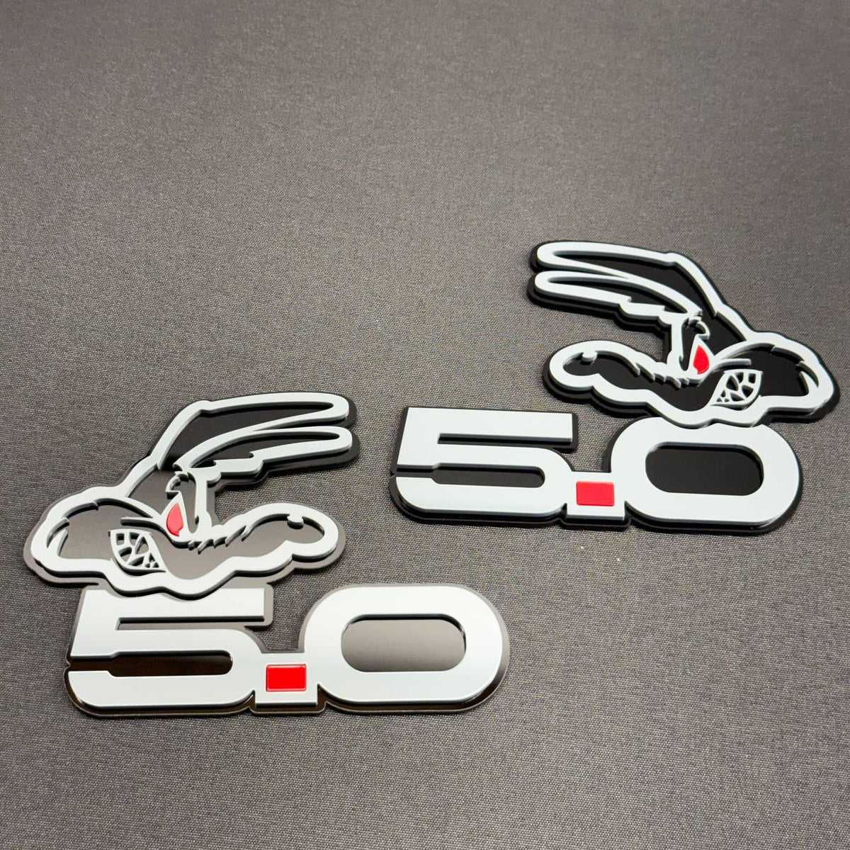 Coyote 5.0 gray car badge with red dot accent, black outlines and cartoon coyote head design for Ford Mustang GT fender customization.
