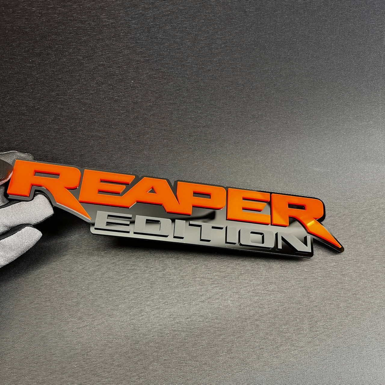 Layered Reaper Edition car badge with black base and gray edition text