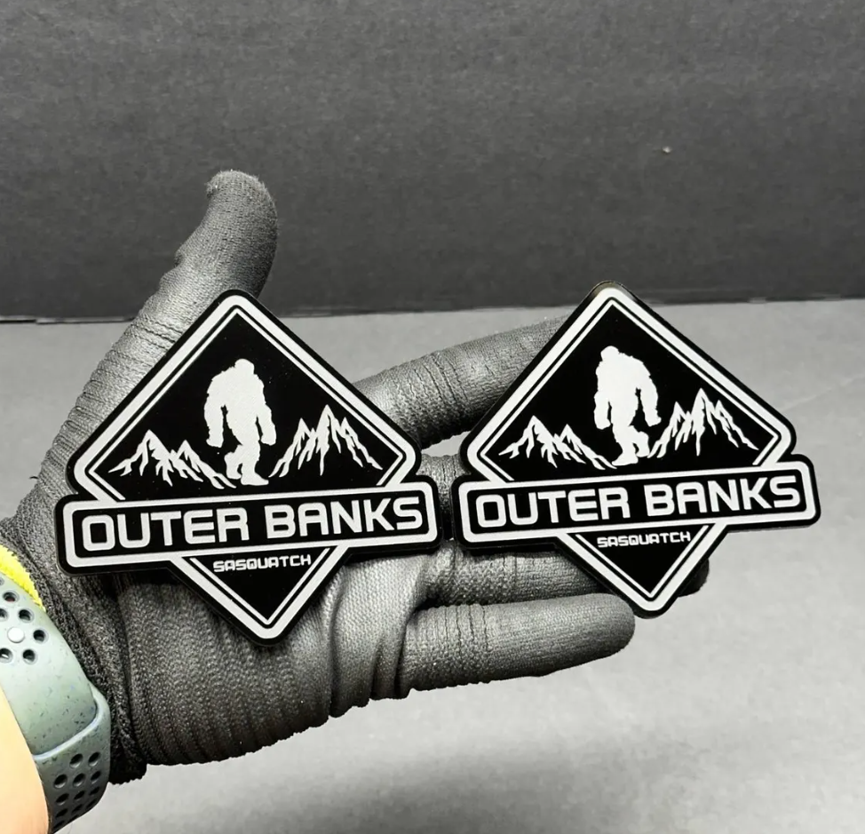 Custom Sasquatch mountain car emblem with black engraved details and brushed metal look