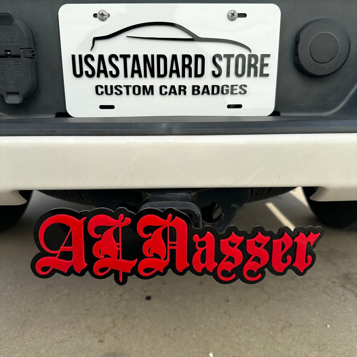 Custom text hitch cover with red lettering and black backing mounted on truck receiver