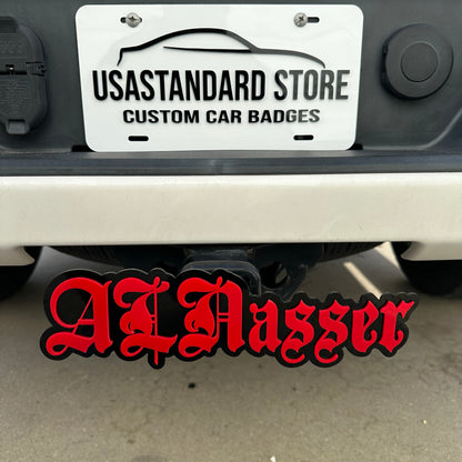 Custom text hitch cover with red lettering and black backing mounted on truck receiver