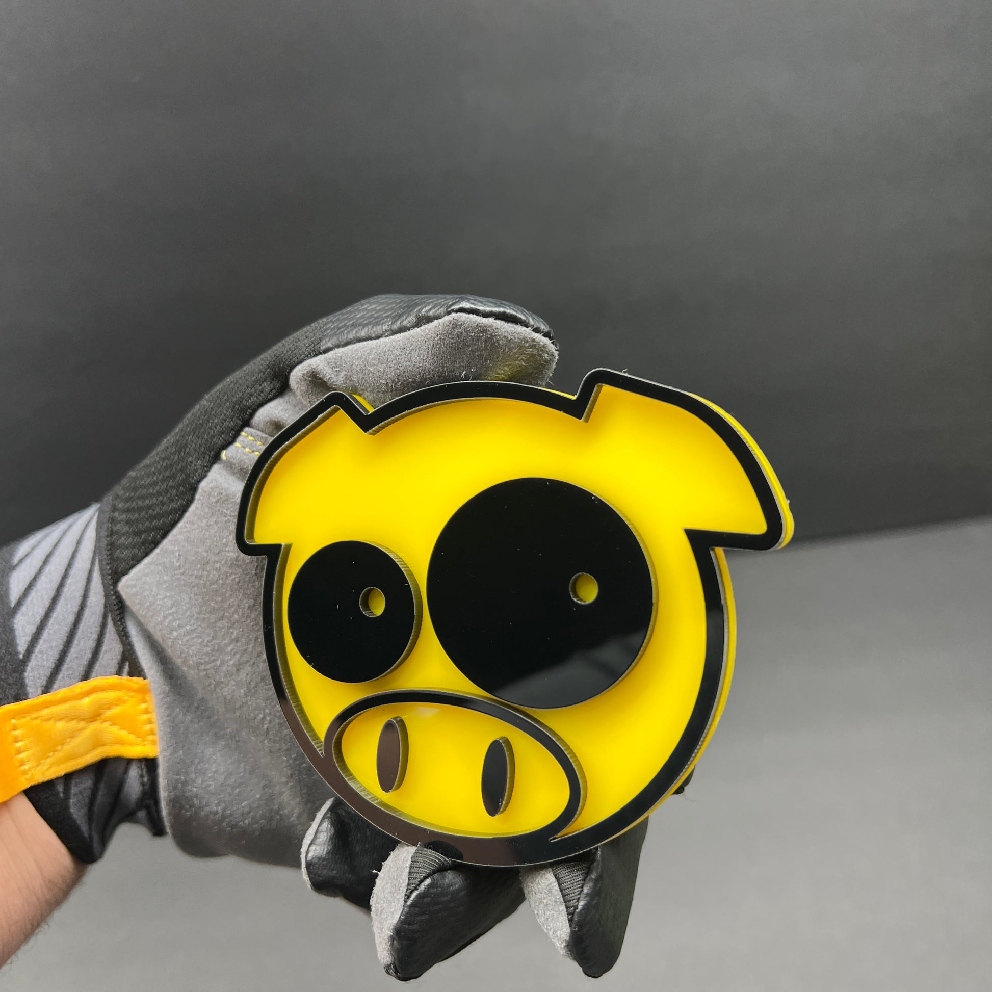 Yellow pig face badge with black raised details for automotive decoration