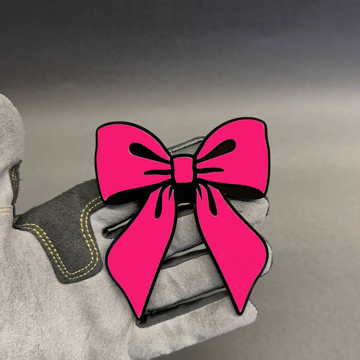 Pink bow tie car badge with bright pink acrylic design and black outline, cute coquette aesthetic automotive emblem.