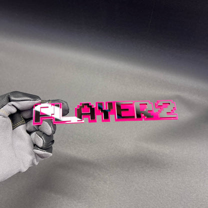 Custom PLAYER 2 text car badge with gaming inspired pixel font design.