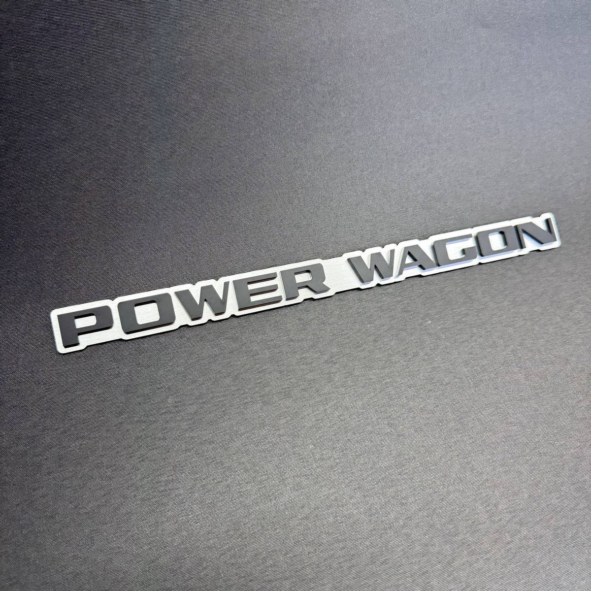 Power Wagon aftermarket decorative badge for Ram 2500 and 3500 pickup trucks, custom silver background with black lettering.