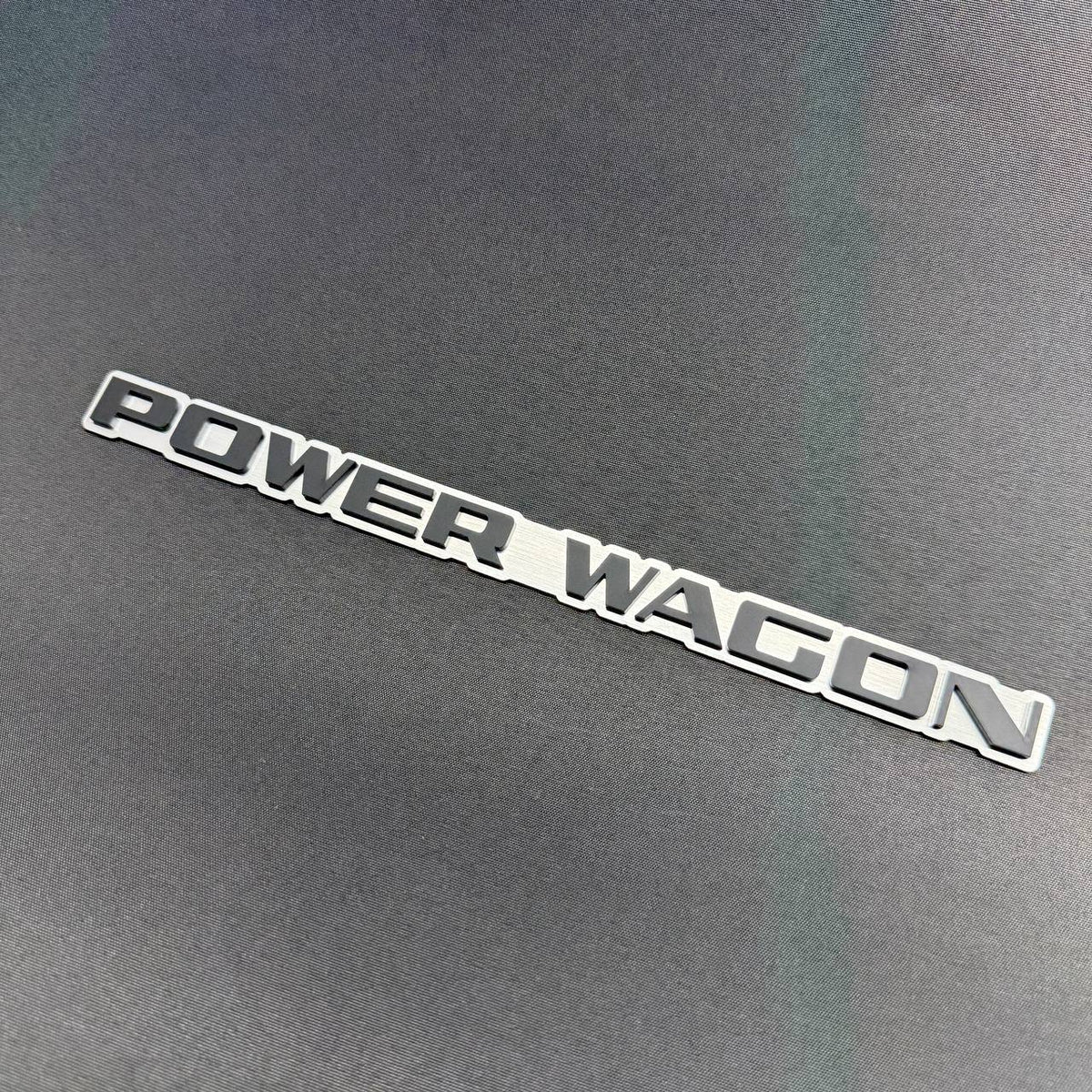 Ram Power Wagon 4WD truck tailgate nameplate emblem, double layer automotive badge with bold raised text.