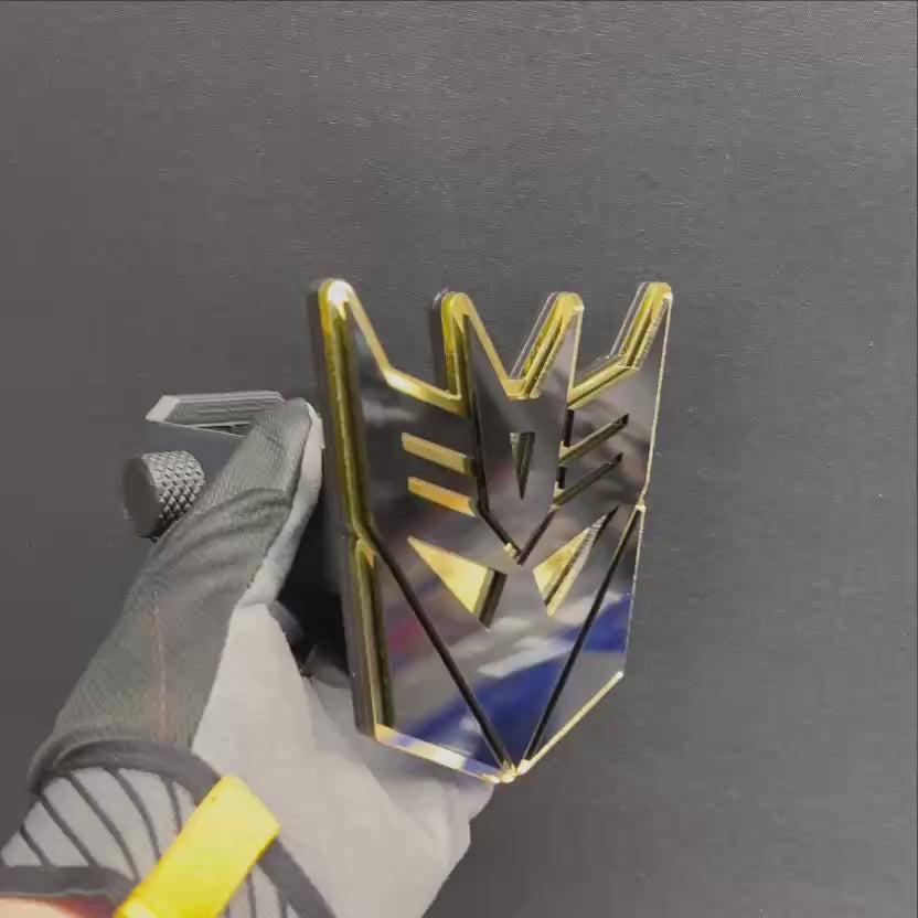 Decepticon style hitch cover with glossy black and mirror gold layered emblem.