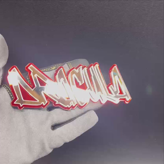 Custom DRACULA text car emblem in reflective chrome with a bright red border