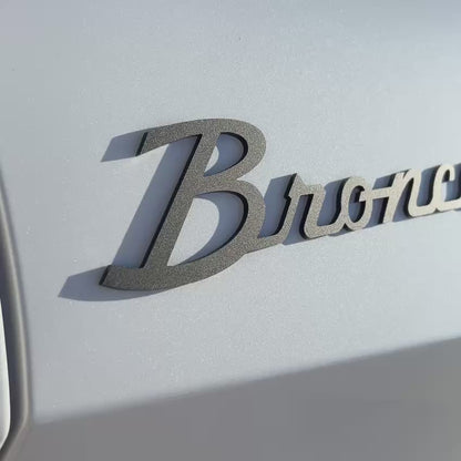 Close-up showcase of gloss black layered script-style badge with 3D effect