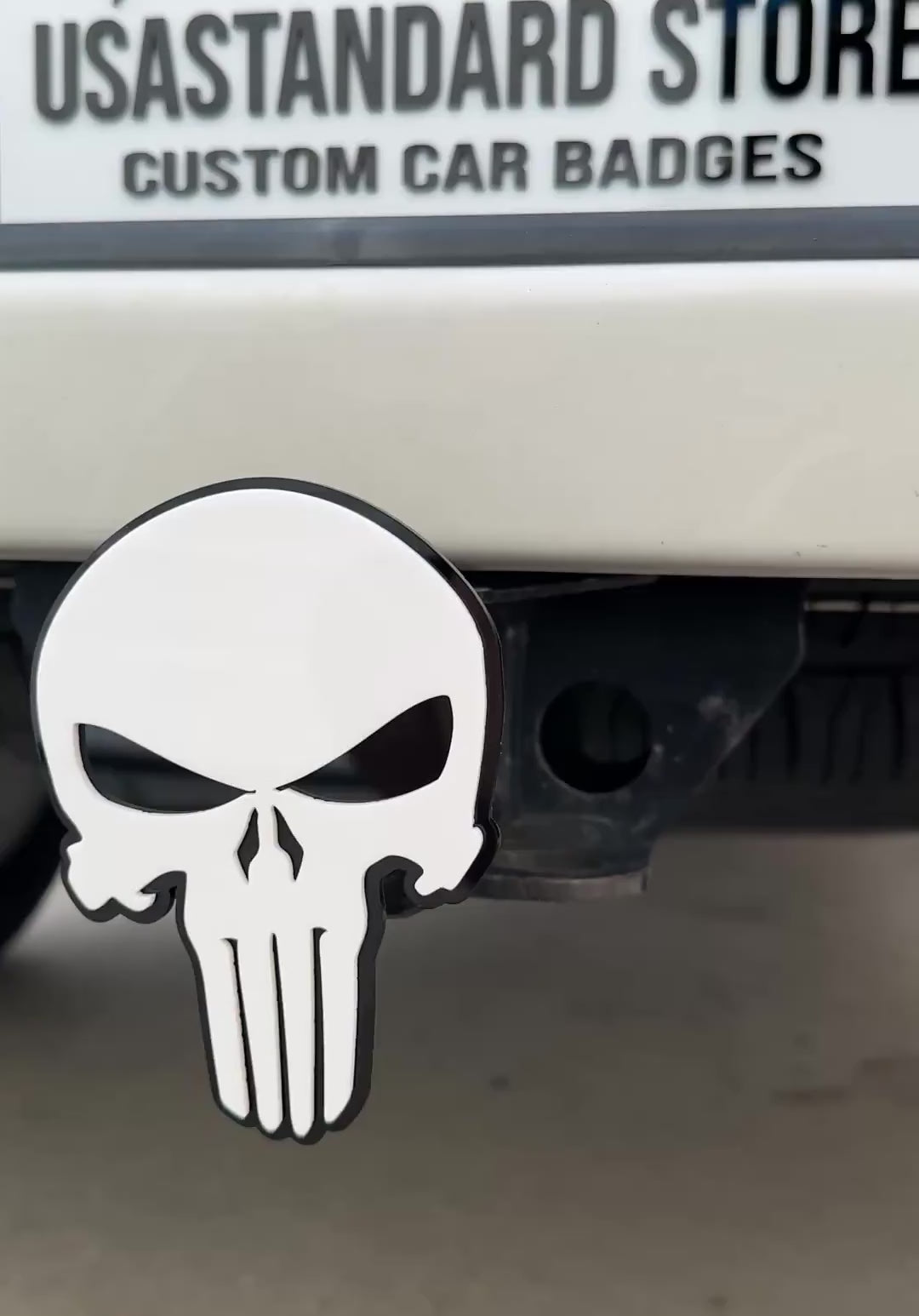 White and black Punisher skull hitch cover emblem mounted on truck receiver