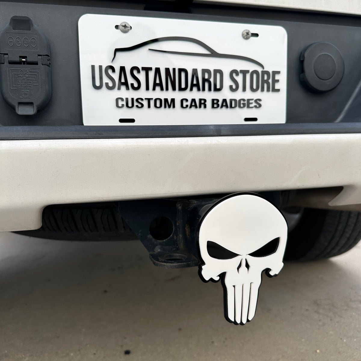 White Punisher skull receiver hitch cover with black border installed on vehicle